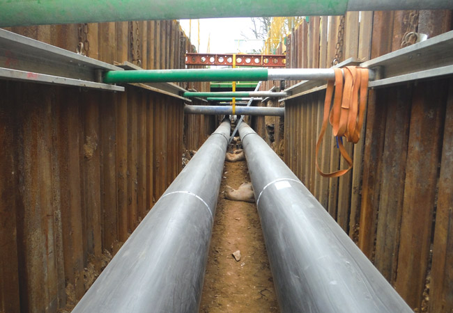 Welder Welding Heat Pipes In Trench. Weldin Insulated Pipes To